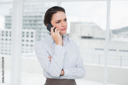 Serious elegant businesswoman using cellphone in office