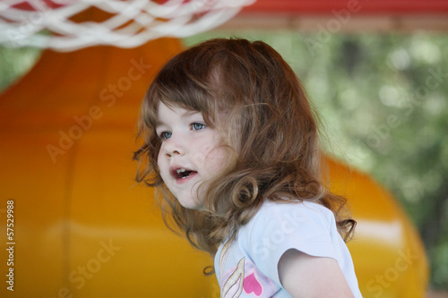 Little pretty happy girl in yellow inflatable trampoline
