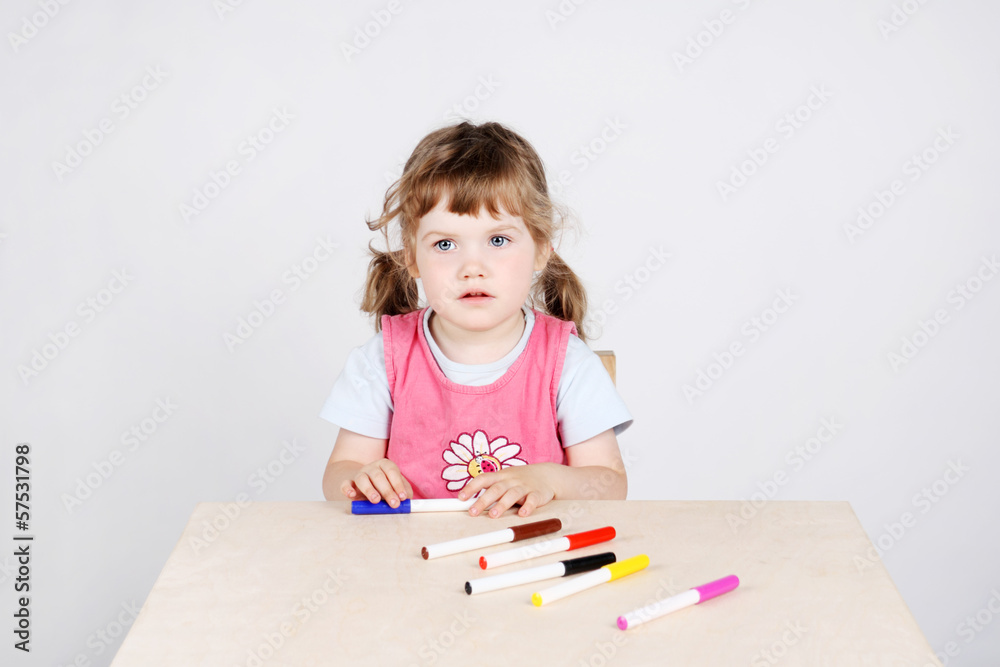 Little cute girl sits at wooden table with felt-tip pens Little cute girl sits at wooden table with felt-tip pens
