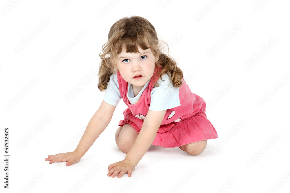 Little pretty girl sits on floor and looks at camera isolated on