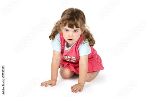 Little surprised girl sits on floor and looks away isolated on w