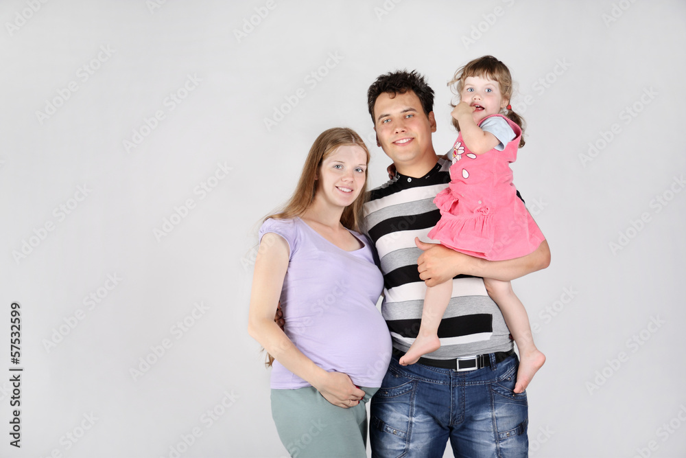 Pregnant mother, happy father and daughter on grey background. Pregnant mother, happy father and daughter on grey background.