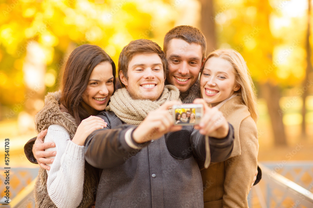 Obraz premium group of friends with photo camera in autumn park