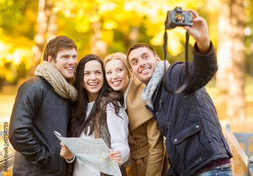 group of friends with photo camera in autumn park