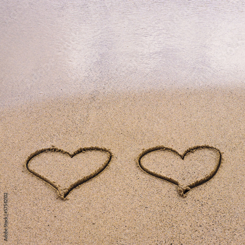 Symbols of two hearts drawn on sand, love concept