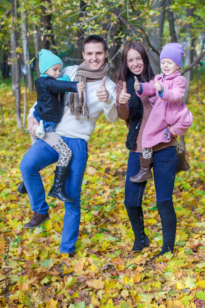 Fototapeta premium Young parents with two little daughters in autumn yellow park