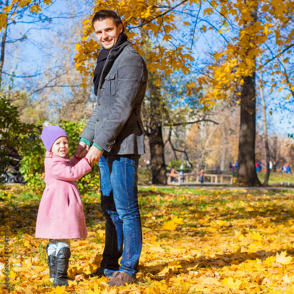 Adorable little girl with happy father in park at autumn