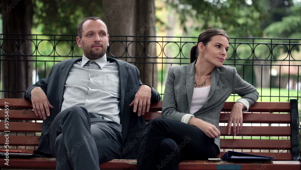Young business people relaxing, sitting on bench in park Young business people relaxing, sitting on bench in park