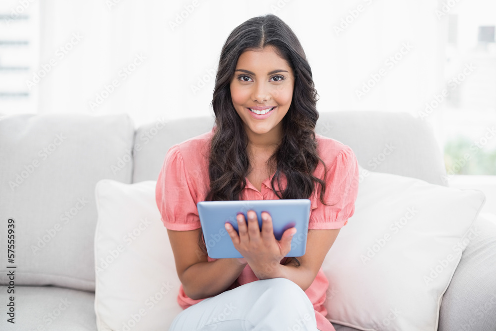 Happy cute brunette sitting on couch using tablet Happy cute brunette sitting on couch using tablet