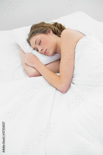 Lovely sleeping woman lying under the cover on her white bed
