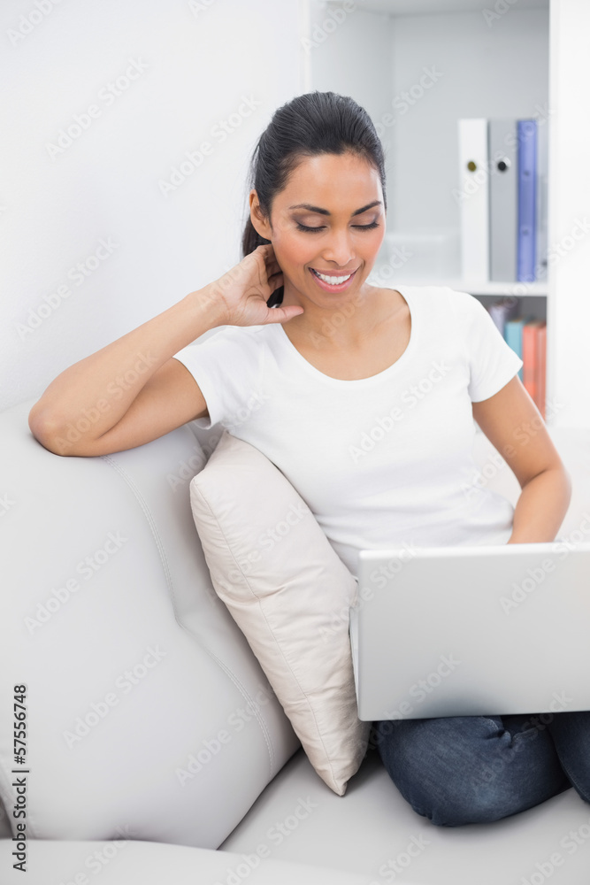 Lovely young woman using her laptop while sitting in couch Lovely young woman using her laptop while sitting in couch