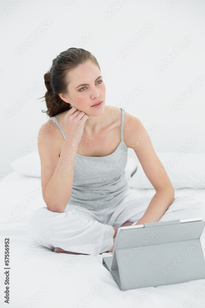 Woman with tablet PC looking away in bed Woman with tablet PC looking away in bed