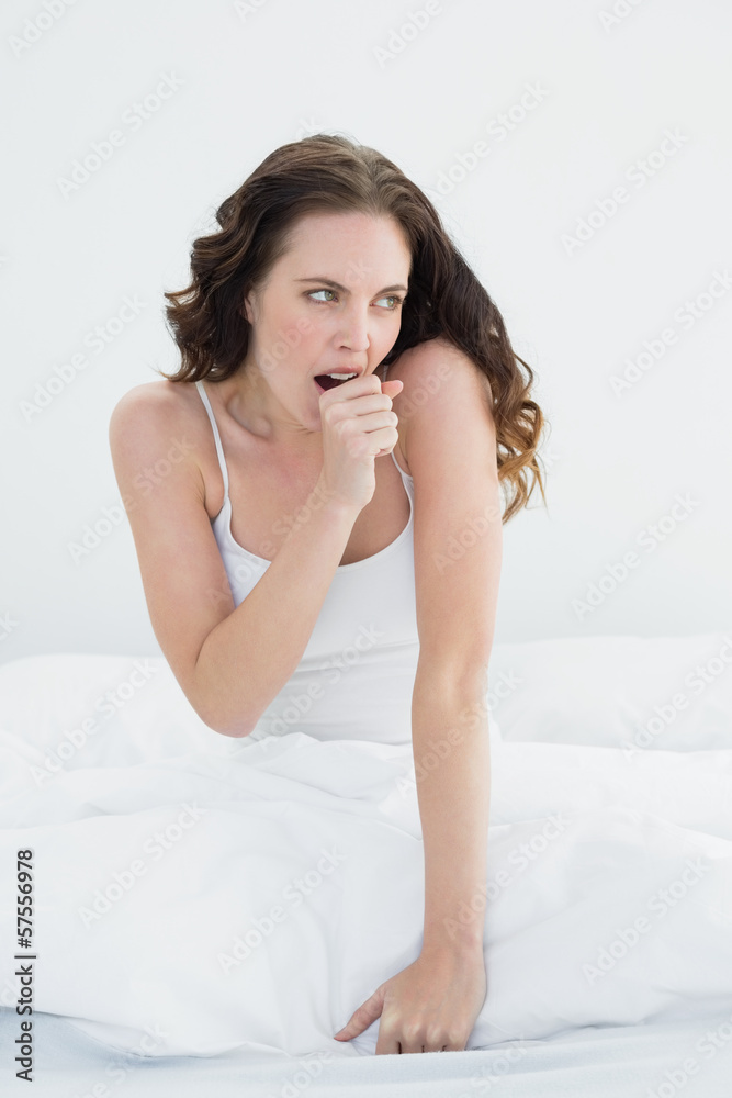 Woman sitting and yawning in bed Woman sitting and yawning in bed