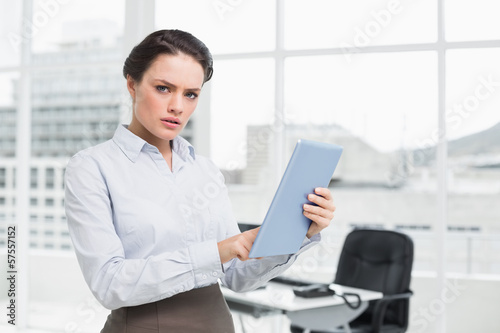 Serious businesswoman using table PC in office © lightwavemedia