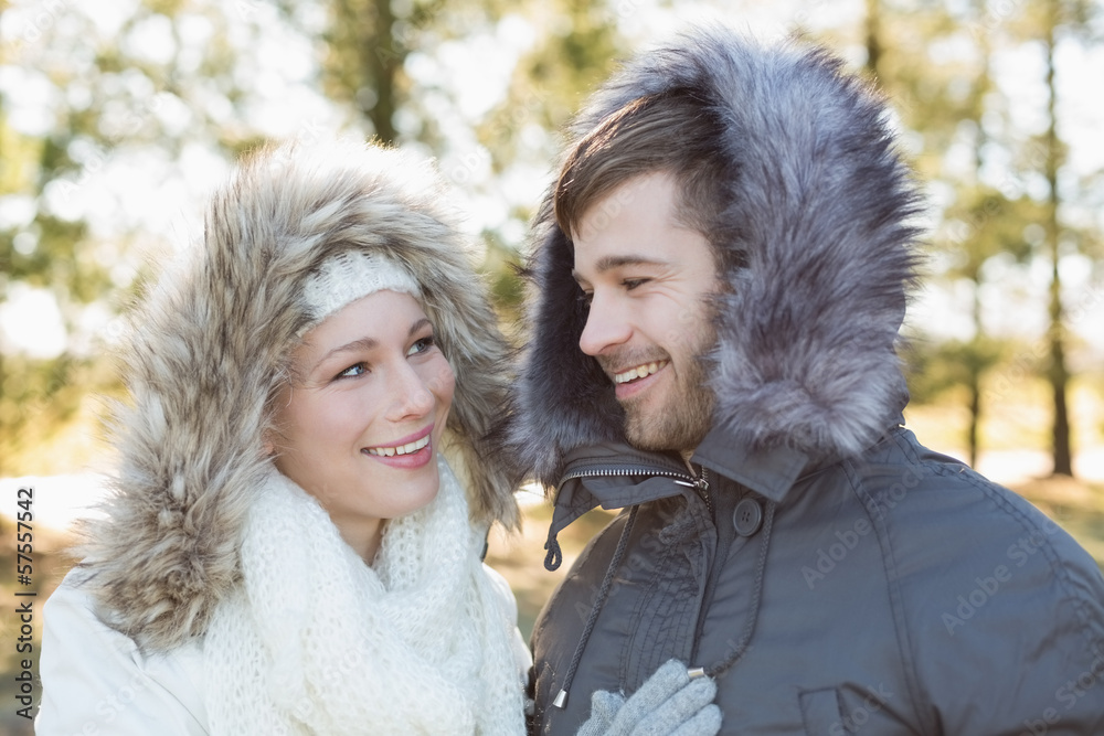 Smiling couple in fur hood jackets in the woods Smiling couple in fur hood jackets in the woods