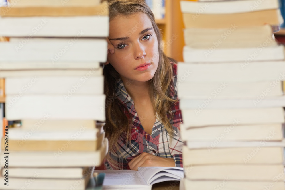 Stern pretty student studying between piles of books Stern pretty student studying between piles of books