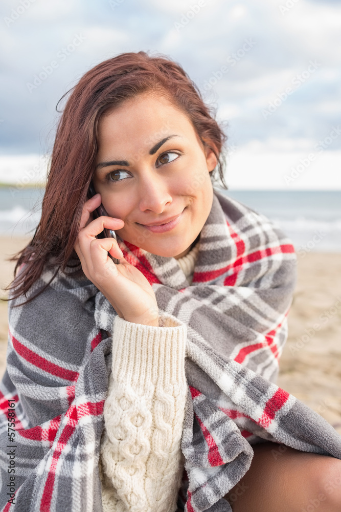 Woman covered with blanket using cellphone at beach Woman covered with blanket using cellphone at beach