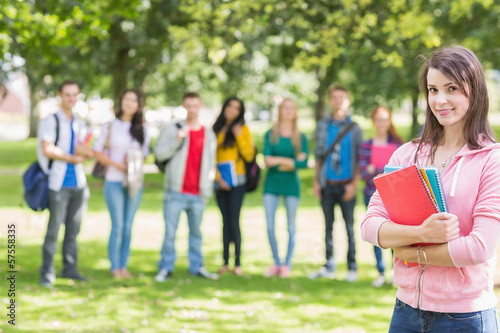 College girl holding books with students in park