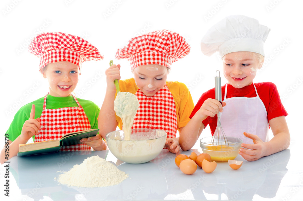 Kids with chef hats preparing tha cake dough Kids with chef hats preparing tha cake dough