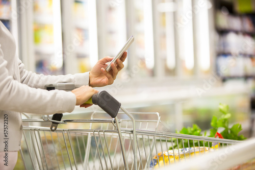 Woman using mobile phone while shopping in supermarket photo
