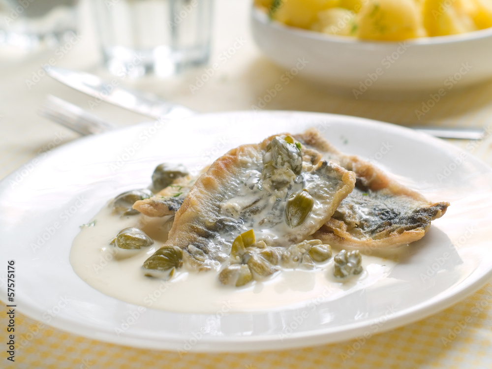Fish fillet with lemon sauce and capers, selective focus