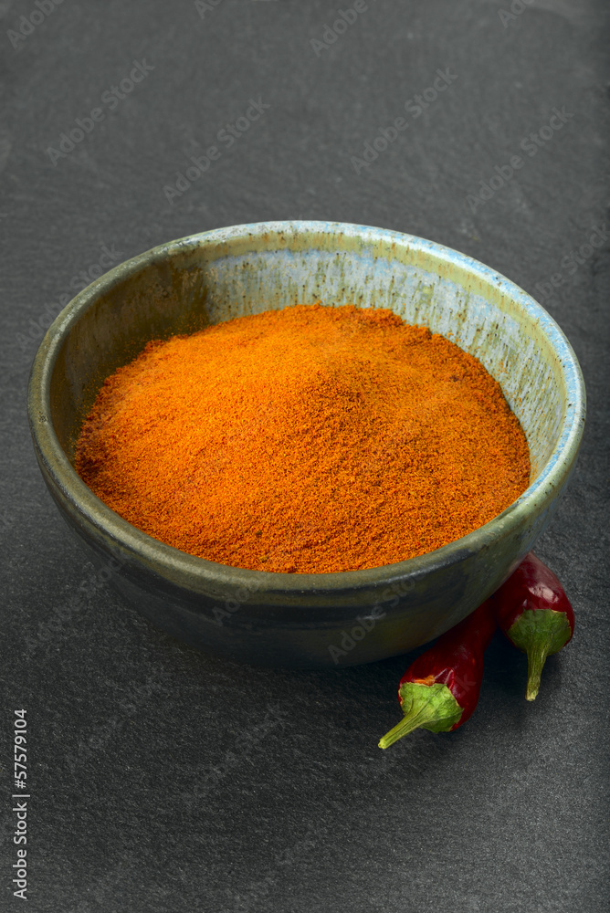 Bowl with pepper powder and two red cayenne peppers Bowl with pepper powder and two red cayenne peppers