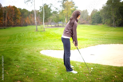 Woman player training on golf course, preparing to shot