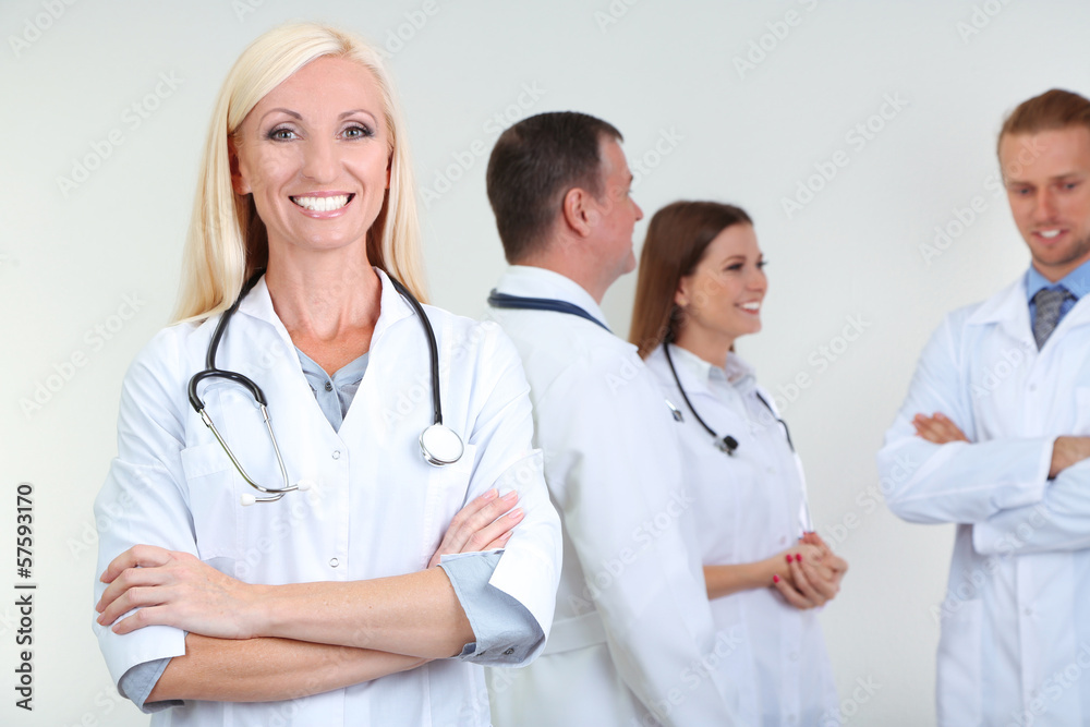 Doctor standing in front of coworkers on grey background Doctor standing in front of coworkers on grey background
