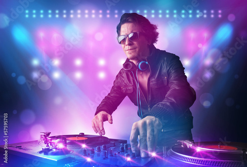 Disc jockey mixing music on turntables on stage with lights and