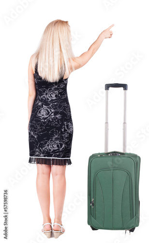 Back view of young brunette woman traveling with suitcas and poi