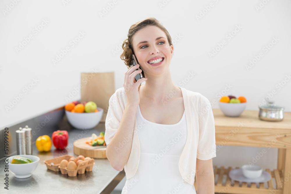 Happy cute woman phoning standing in her kitchen