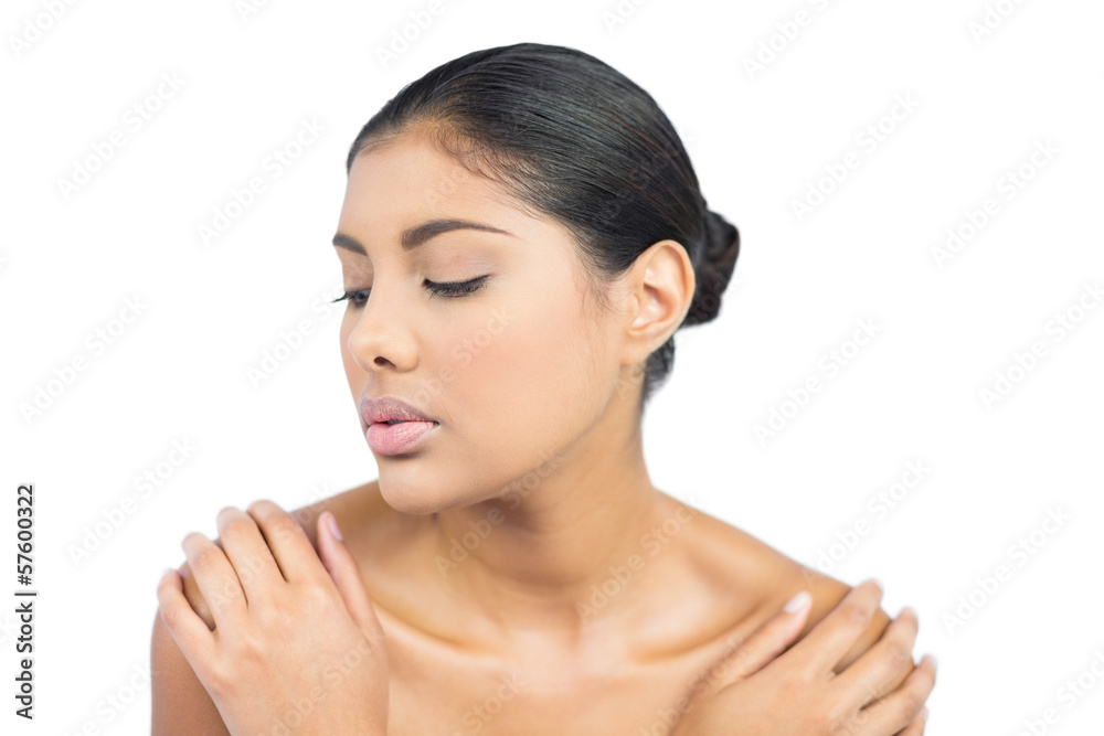 Calm nude brunette holding shoulders with closed eyes