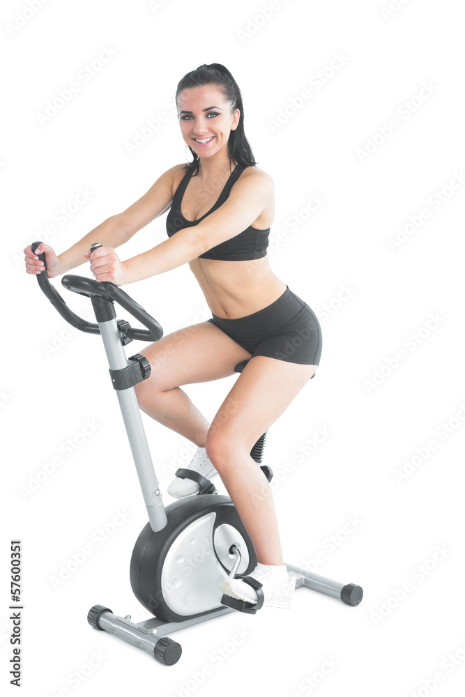 Fototapeta premium Cheerful ponytailed sporty woman training on an exercise bike