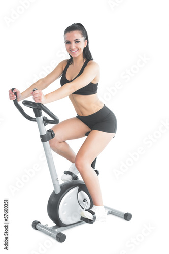 Cheerful ponytailed sporty woman training on an exercise bike