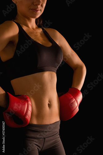 Mid section of young sporty woman posing and wearing boxing glov