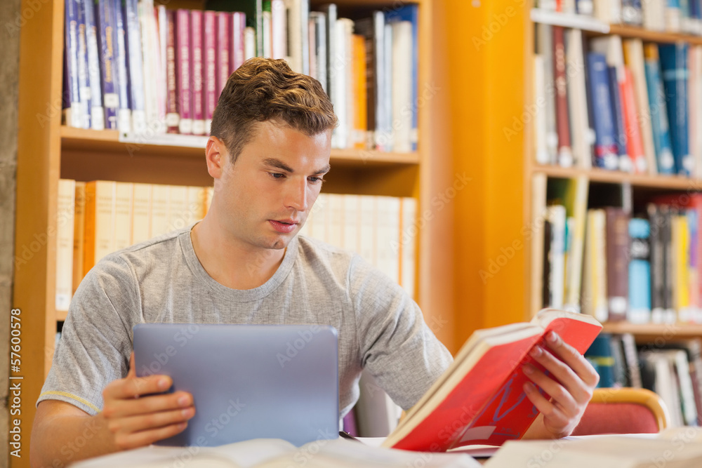 Attractive smiling student using tablet and holding book Attractive smiling student using tablet and holding book