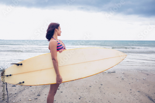Woman carrying surfboard on the beach