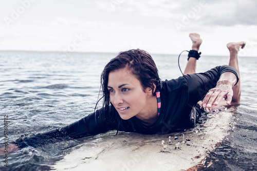Photography Young woman swimming over surfboard in water
