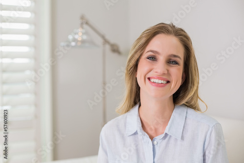 Casual cheerful blonde sitting on couch looking at camera