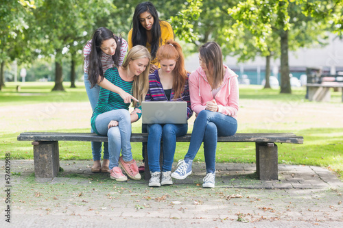 Young college girls using laptop in park