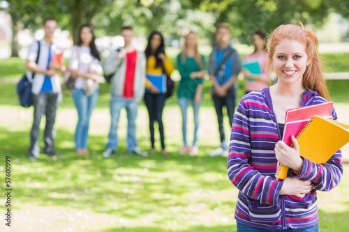 College girl holding books with students in park