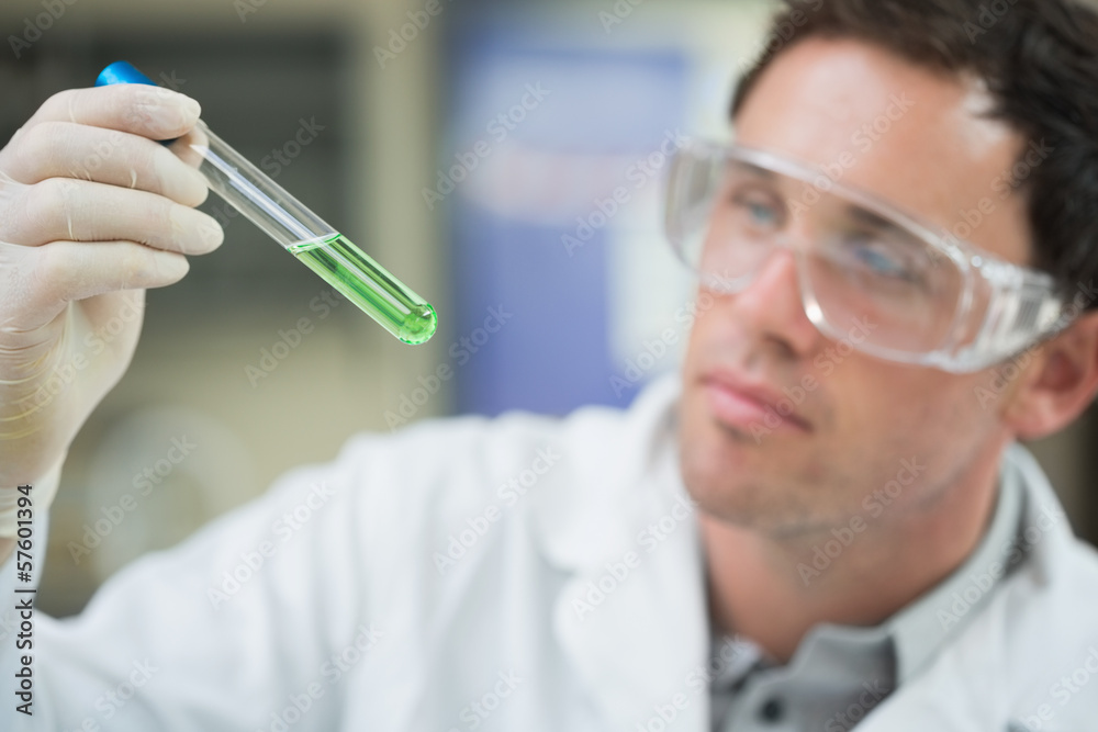 Scientist analyzing green solution in test tube at laboratory Scientist analyzing green solution in test tube at laboratory