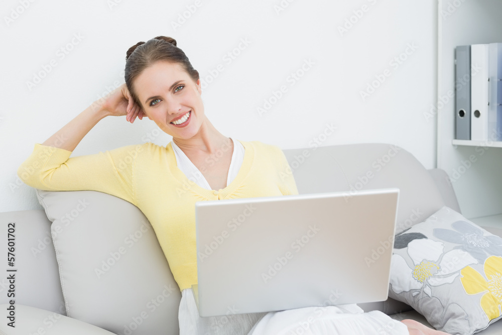 Smiling casual woman with laptop sitting at home