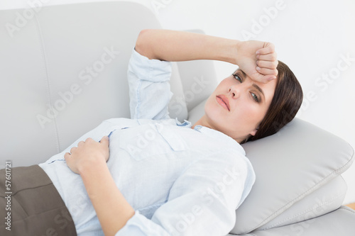 Serious well dressed woman lying on sofa