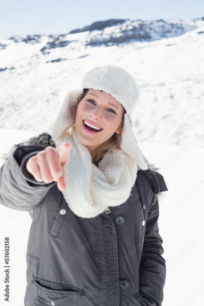 Woman in warm clothing pointing at camera on snow covered landsc Woman in warm clothing pointing at camera on snow covered landsc