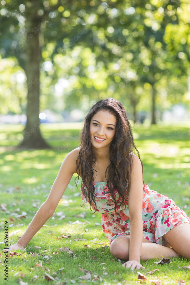 Stylish cheerful brunette sitting on grass