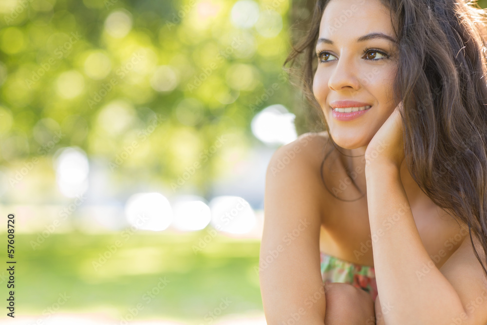 Stylish beautiful brunette sitting under a tree