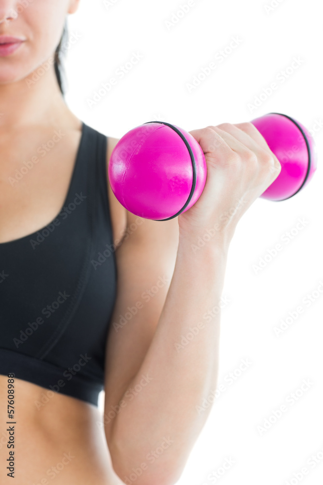 Mid section of slender active woman training her arm with a pink Mid section of slender active woman training her arm with a pink
