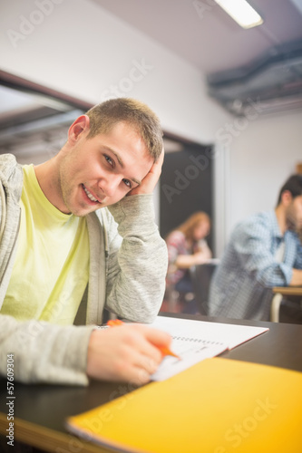 Male student with others writing notes in classroom