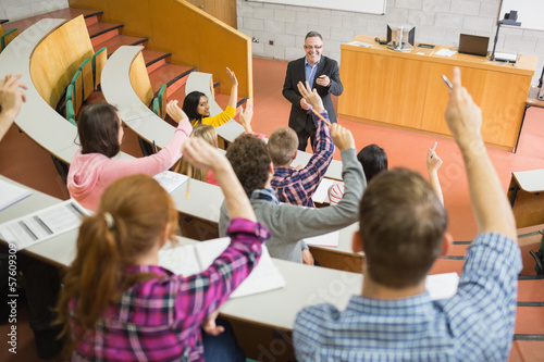 Fotografi Students raising hands with teacher in the lecture hall